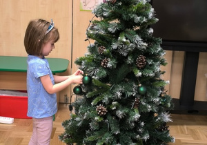 Dziewczynka zawiesza bombkę na choince