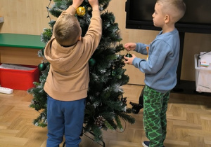 Chłopcy zawieszają bombki na choince
