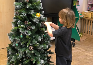 Chłopiec zawiesza bombkę na choince