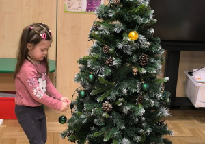 Dziewczynka zawiesza bombkę na choince