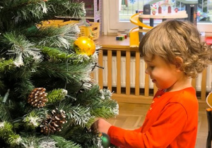 Chłopiec zawiesza bombkę na choince
