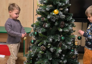 Chłopcy zawieszają bombki na choince