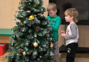 Chłopcy zawieszają bombki na choince