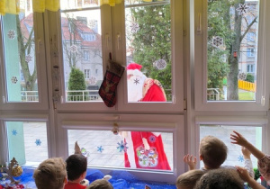 Dzieci patrzą przez okno na Świętego Mikołaja
