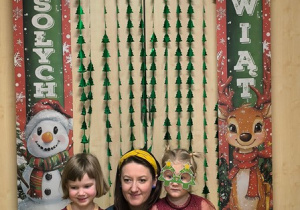 Dziewczynki i mama stoją na tle świątecznej dekoracji