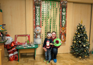 Chłopiec z mamą pozują do zdjęcia na tla świątecznej dekoracji