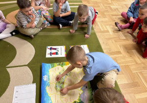 Chłopiec przykleja na mapę Polski kontur województwa kujawsko-pomorskiego