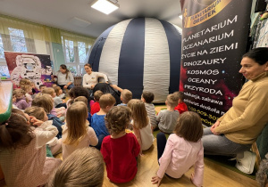 Dzieci siedzą przed balonowym planetarium