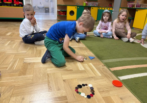 Chłopiec układa z guzików kontur trójkąta