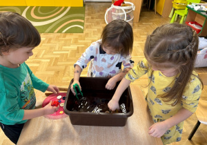 Dzieci wyciągają szczypcami guziki zanurzone w wodzie