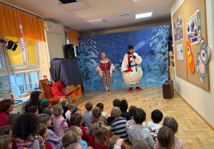 Dzieci siedzą na podłodze i ogladają przedstawienie