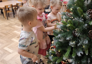 Dzieci stroją choinkę w ozdoby świąteczne