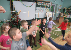 Dzieci odpinają spinacze przyczepione do sznurka.