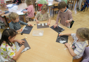 Dzieci przy stolikach wykonują prace plastyczne.