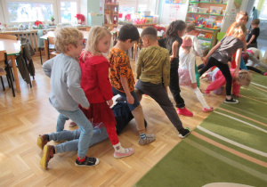 Dzieci przechodzą przez tynel, który tworzą stojąc w rzędzie.