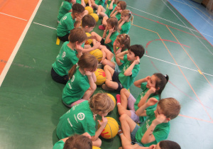 Dzieci siedzą w parach na przeciwko siebie.