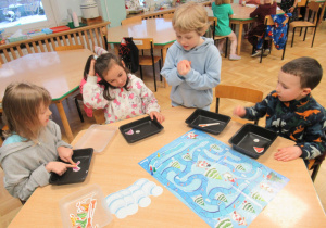 Dzieci siedzą przy stoliku i grają w grę.