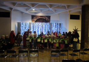 Dzieci pozują do zdjęcia z seniorami.