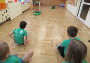 Dziewczynki jadą na jeździkach gimnastycznych.