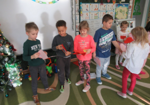 Dzieci wręczają sobie laurki wykonane dla kolegów lub koleżanek z grupy.