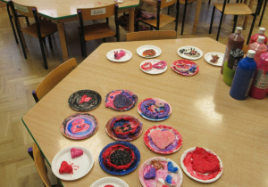 Serca z masy solnej, dziewczynka siedzi przy stoliku i maluje serce z masy solnej.