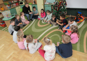 Dzieci siedzą w kole podczas zajęć języka angielskiego.