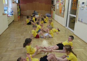 Dzieci ćwiczą w parach na zajęciach z elementami teakwondo.