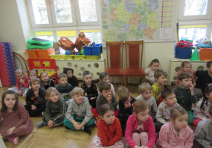 Dzieci siedzą na podłodze.