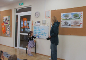 Dziewczynka stoi przy tablicy i przelicza śnieżynki.