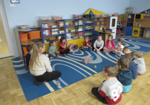 Dzieci siedzą w kole podczas zajęć z języka angielskiego.