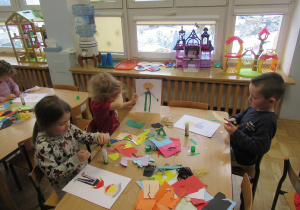 Dzieci przy stolikach wykonują prace plastyczne.