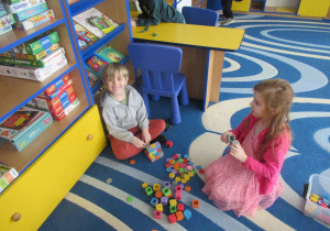 Chłopiec i dziewczynka bawią się klockami na dywanie.