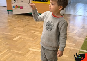 Chłopiec trzyma planszę z cyfrą 5