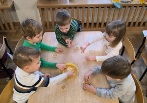 Dzieci przekładają ziarenka do małych pojemników