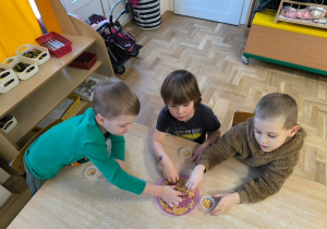 Dzieci przekładają ziarenka do małych pojemników