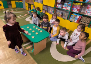 Dziewczynka przelicza pojemniki z ziarenkami