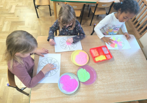 Dzieci wykonują mandale z wykorzystaniem kolorowej soli