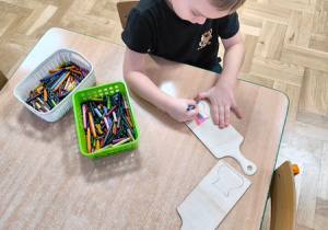 Chłopiec dekoruje drewnianą deskę