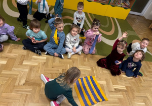 Dziewczynka układa naprzemiennie szarfy żółte i niebieskie symbolizujące dzień i noc