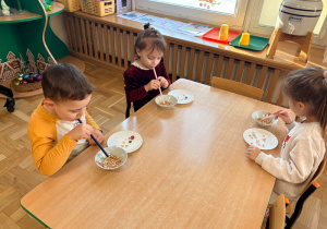 Dzieci przenoszą płatki orkiszowe za pomocą słomek