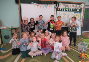 Dzieci pozują do zdjęcia w sali przedszkolnej.