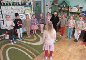 Dzieci stoją w szeregu i trzymają w rękach instrumenty.