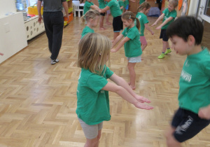 Dzieci ćwiczą w parach podczas zajęć gimnastycznych z elementami taekwondo.