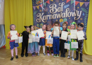 Dzieci pozują do zdjęcia z dyplomami i upominkami.