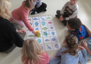 Dzieci siedzą na podłodze podczas zajęć z robotami edukacyjnymi.