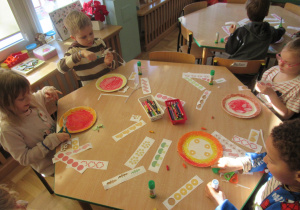 Dzieci wykonują prace plastyczne - pizze z talerzyków.