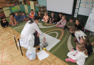 Dzieci siedzą w półkolu podczas warszatatów Labo.