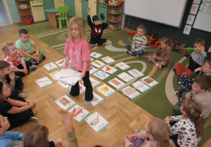 Dzieci siedzą w kole, przed nimi obrazki.