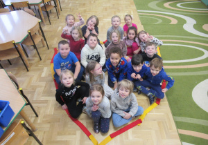 Dzieci siedzą w sercu ułożonym z szarf.