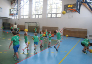 Dzieci rzucają piłki do kosza.